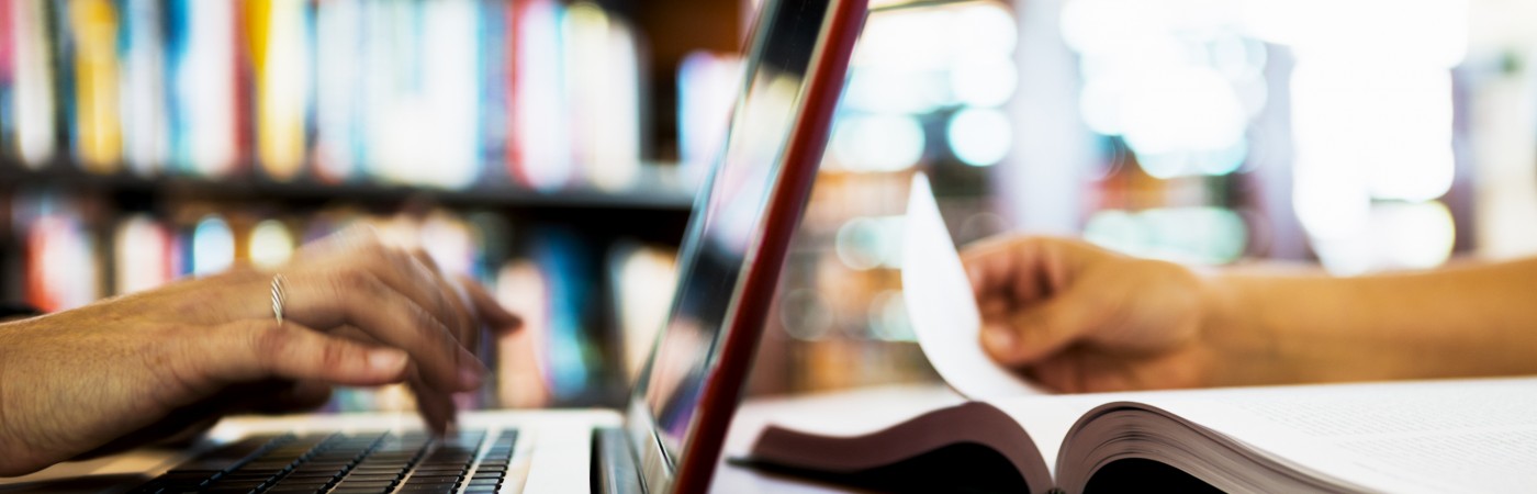 Two people working with computer and book.